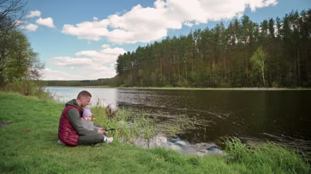 Familienangeln, Vater angelt mit Kleinkind-Tochter am ruhigen Fluss mit Retro-Bambusrute — Stockvideo