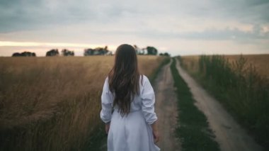 Uzun saçlı güzel bir kız yazın buğday tarlasında yürür, elleriyle buğday kulaklarına dokunur, çiftçi kadın kollarını açar, buğday tarlasında yürür, iyi tahıl hasadına sevinir.