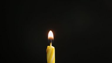Tek büyük sarı mum ışıkları ve söndürme, siyah arka planda izole edilmiş, yavaş çekim, merkezi çerçeve kapatma, 4k