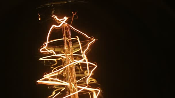 De gloeilamp Edison met een wolfraam gloeidraad helderder en bewegend swingend tijdens het spinnen. Geel licht over zwarte achtergrond rotatie, van dichtbij bekijken. Onthulling details van bokeh, 4k. — Stockvideo
