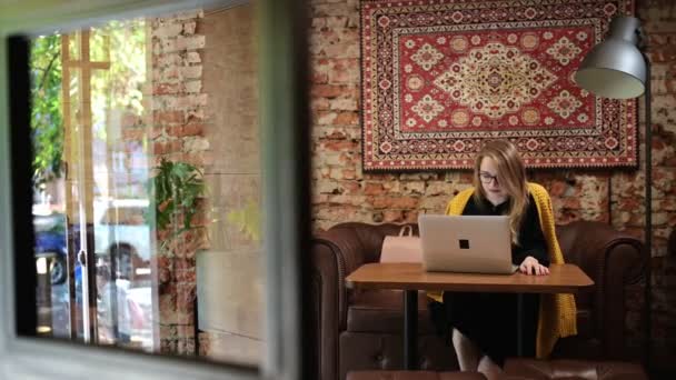 Genç kadın serbest tablet dizüstü bilgisayar ile taşınabilir bilgisayar ile masada tek başına otururken gülümseyerek yazarak çalışıyor. İnsanlar ve modern teknoloji kavramı. — Stok video