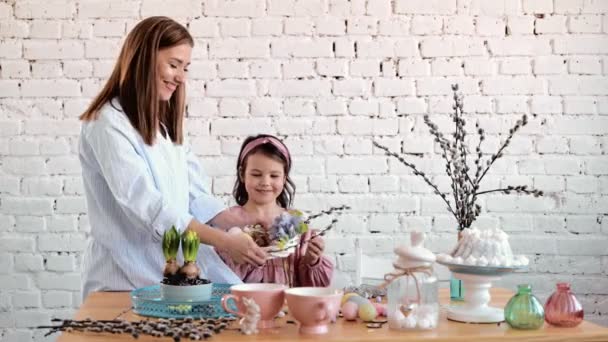 Jeune femme et enfant pose Pâques table de fête avec lapin et oeufs couronne de décoration — Video