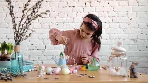 Jolie jolie enfant fille qui s'amuse pendant la peinture des œufs pour Pâques au printemps à la maison. Enfant peignant des œufs. Bonne famille se préparant pour Pâques tout en appréciant la décoration bricolage à la maison. 4K — Video