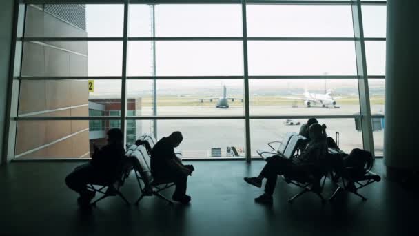 Waiting for flight at airport. Mans sitting on chair in airport lounge. Flights canceled. Problems with flights during quarantine. The collapse of airlines. Covid 19, coronavirus, Silhouette of people — Video