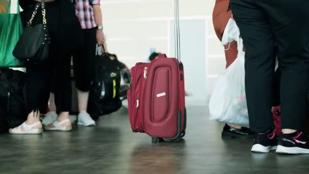 Mala vermelha no aeroporto contra o pano de fundo de pessoas caminhando voltas do tempo, 4k — Vídeo de Stock