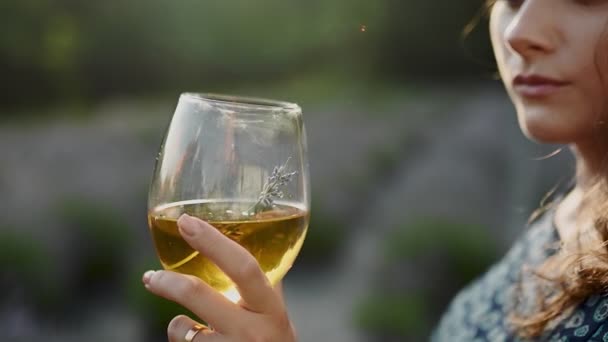 Una mujer sostiene una copa de vino tinto al atardecer. Sobre el fondo de la viña. Los turistas están probando el concepto de vino, cámara lenta — Vídeos de Stock