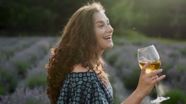 Açık havada elinde bir kadeh şarap tutan neşeli beyaz kadın şehirde güneşli bir gün tatili yapmaktan memnun.