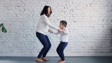 Aktif bir anne, bebek bakıcısı ve küçük tatlı bir çocuk modern evde dans ediyor, mutlu bir aile annesi ve kız çocuğu evde eğlenceli vakit geçiriyorlar.