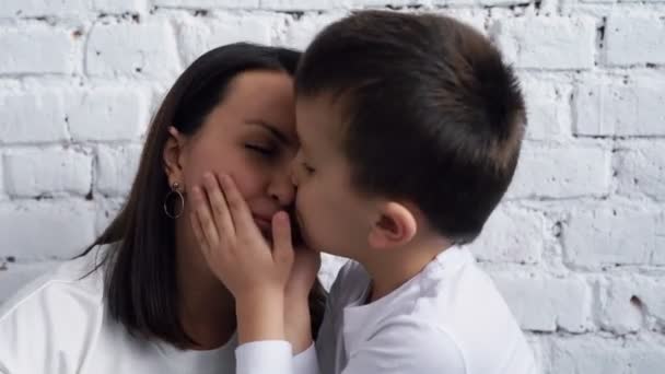 Funny kid kiss happy laughing mum greeting female parent with mother day or birthday, little son kisses mom, Little son kisses mom, Young caucasian family together at home on weekend or lockdown spend — Stock Video