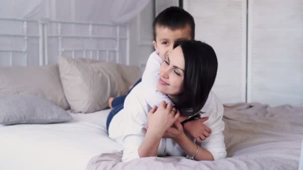 Liebevolle Mutter, die ihr Kind umarmt und liebenswert hält im modernen heimischen Wohnzimmer, glückliche Mutter, die ihr Kind küsst und pflegt, Konzept der Kindheit, Neues Leben, Elternschaft, Nahaufnahme — Stockvideo