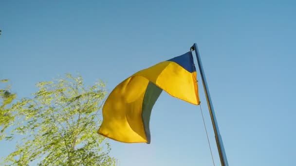 Movimiento lento de la bandera de Ucrania ondeando fondo azul cielo y amarillo color nacional ucraniano amarillo-azul. Bandera de Ucrania viento ondeando país símbolo nacional. Bandera de textura de tela altamente detallada de Ucrania — Vídeos de Stock