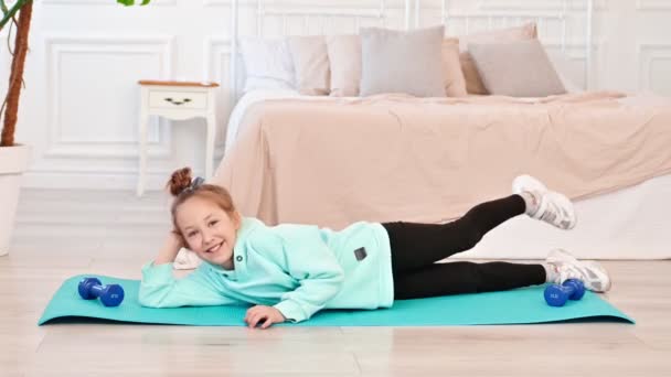 Happy smiling girl is engaged in a spot at home on a sports mat. Distance learning. Dvty and sports exercises, Slow motion — Video Stock