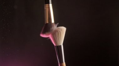 Close up selective focus shot of shimmer powder being shaken off makeup brush, Slow motion
