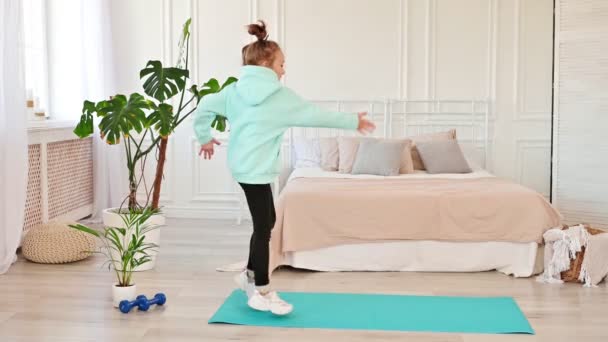 Happy child dancing in the living room on a sports mat, long hair, the girl feels good and excited. Children and sports, Slow motion — Video Stock