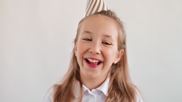 Cheerful cute girl in cap laughs look on camera. The daughter smiles. Happy childhood concept. Portrait of a preschool girl on a white background. Slow motion — Wideo stockowe