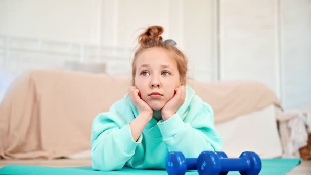 Trauriges Mädchen 8-10 Jahre alter Teenager schlechte Laune. Aufgebrachtes Mädchen liegt auf einer Sportmatte. Kinder und Freizeit. Sport im Kinderleben. — Stockvideo