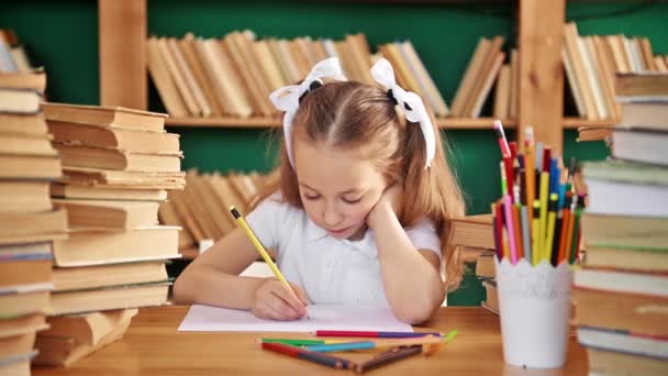 A focused child is engaged in the library. Blond white girl with ponytails 8-10 years old in the library. — Stock Video