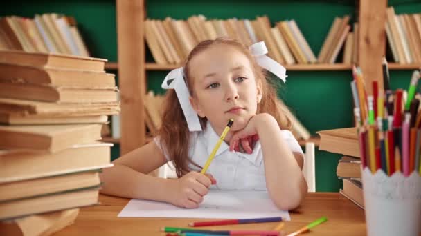 Uma criança focada está envolvida na biblioteca. Menina branca loira com rabo de cavalo 8-10 anos na biblioteca. — Vídeo de Stock