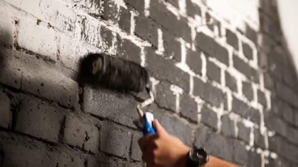 Close Up Shot of Black Paint este aplicat pe un perete. Conceptul de renovare la domiciliu. Pictor om pictura pictura un perete de cărămidă în casă, cu role de vopsea și vopsea de culoare închisă. Renovarea camerei — Videoclip de stoc