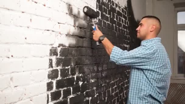 Primer plano de caucásico joven alegre guapo de pie en el apartamento durante la renovación y el rediseño, la pintura de la pared y sonriente Reparación y mejora de la casa redecoración y construcción — Vídeo de stock