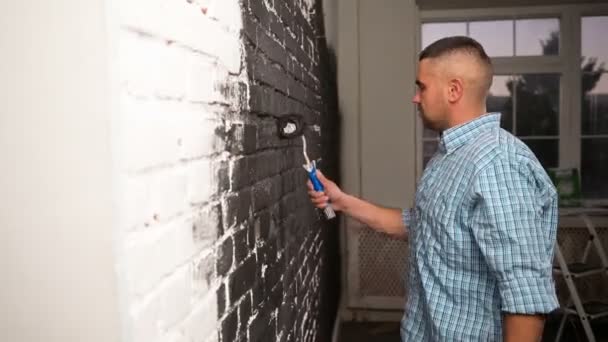Der Mensch macht Reparaturen zu Hause, bemalt die Wand mit weißer Farbe. Renovierung, Familieninterieur. Wandbemalung von Frau mit Farbwalze. Zimmer neu dekorieren — Stockvideo