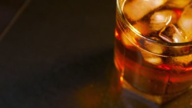 Glass of whiskey and ice swirls top view.