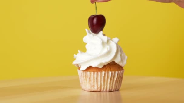 Hand Puts Cherry Cream Cupcake Rotating Yellow Background — Stockvideo