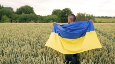 A man walked across the Wheat Field with the Ukrainian flag on his back. Slow motion.