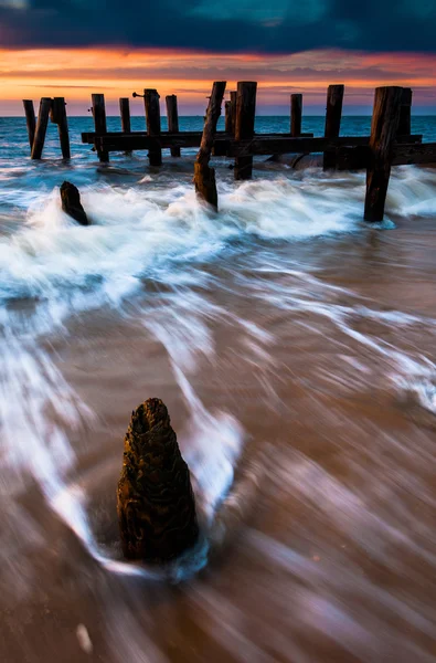 Wellen wirbeln bei Sonnenuntergang um die Molenpfähle in der delaware Bay, — Stockfoto