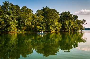 Trees and boat reflecting in Loch Raven Reservoir, near Towson, clipart