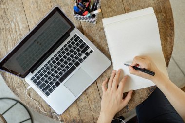 İnternette konsept üzerine çalışan siyah saçlı bir öğrenci internette bilgi arayarak ödevini yapıyor ve bu siyah kalemi kullanarak araştırmasının sonucunu kağıda yazıyor..