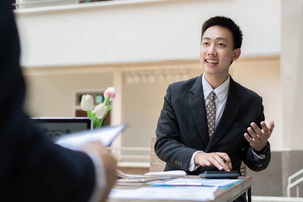 Концепция бизнесмена-офисного работника, работающего над заданием учета с помощью калькулятора и ноутбука внутри здания.