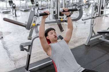 Egzersiz konsepti. Ağırlığı aşağı çekerken, sırtı ağırlık makinesinde yatarken nefesini kontrol etmeye çalışan kaslı adam..