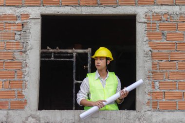 Mühendislik konsepti İnşaatın bazı detaylarını incelerken binanın içinde sert bir yüzle duran planlamacı.