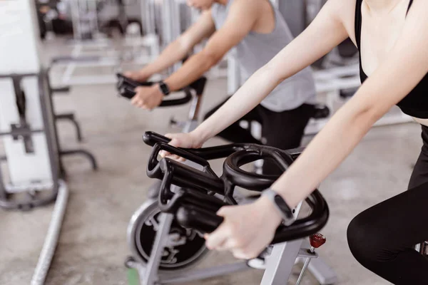 运动理念两个参加运动俱乐部的人玩自行车锻炼机 在彼此旁边做有氧运动 — 图库照片