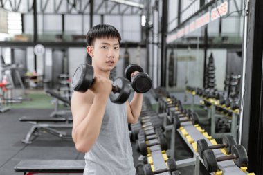 Spor konsepti erkek spor üyesi iki eliyle siyah dambılları kaldırır, ayakta durur ve aynaya bakarken konsantrasyon kıvrımı pozu verir..