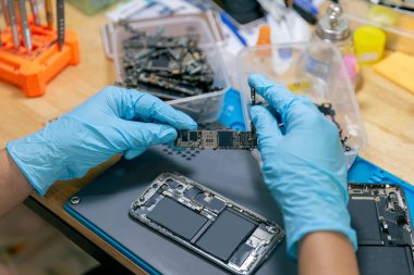 Telefon tamir konsepti. Elektronik kısmı seçen bir tamirci. Masadaki aletlerle cep telefonuyla monte etmek için..