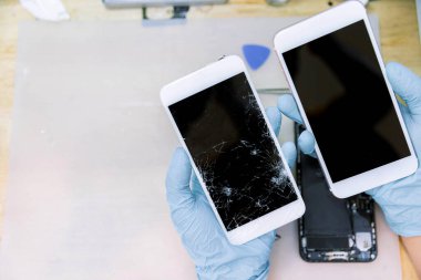 Telefon tamir konsepti. İki el lastik eldiven takıyor. İki akıllı telefon tutuyor..