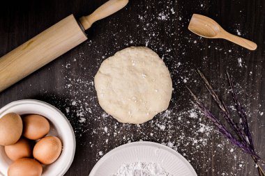 Ekmek kavramı çörek hamuru, minyon ahşap bir spatula, merdane, ve koyu ahşap masada birkaç yumurta..
