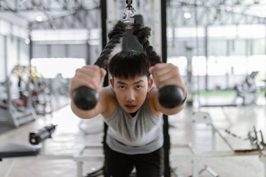 Spor konsepti. Spor kulübünde güç makinesi yapan, kendini eğen ve esnek halatı aşağıya doğru çekmeye çalışan ciddi yüzlü spor adamı..