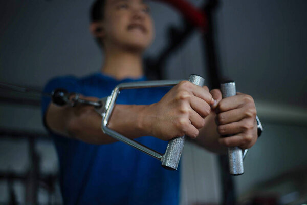 Training gym concept a muscled male teenager using a gym equipment repeating pushing forward for developing his breast.