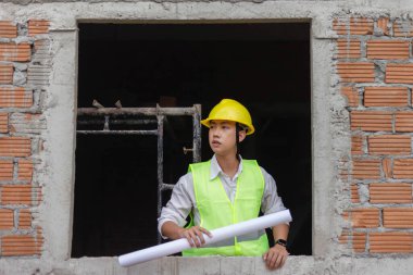 Mühendislik konsepti İnşaatın bazı detaylarını incelerken binanın içinde sert bir yüzle duran planlamacı.