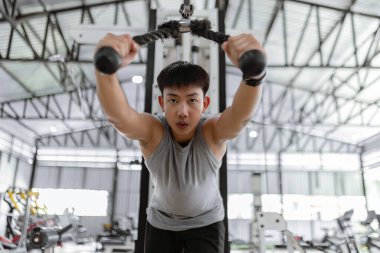 Spor konsepti. Spor kulübünde güç makinesi yapan, kendini eğen ve esnek halatı aşağıya doğru çekmeye çalışan ciddi yüzlü spor adamı..