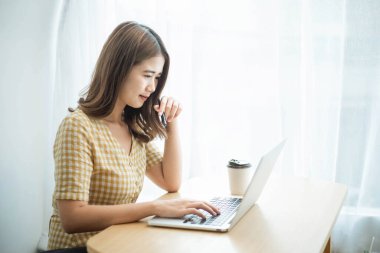 Girişimci konsepti. Genç bir iş kadını, müşterilerine e-posta göndermek için dizüstü bilgisayarda yazı yazıyor..