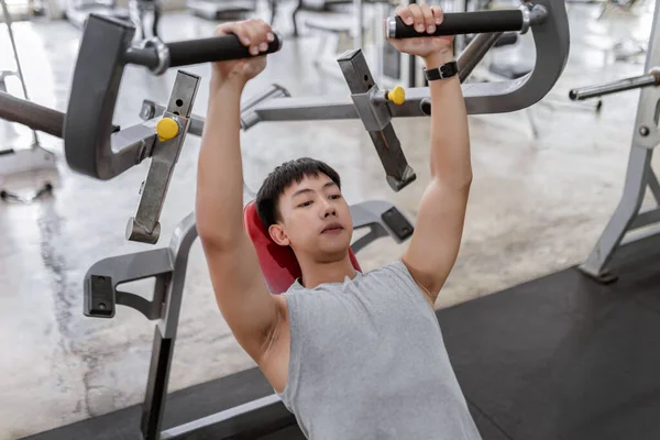 exercise concept The muscly man with earnest face trying to control his breath while lying his back on the weight machine and pulling the weight down.