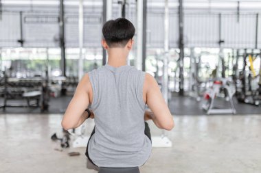 Egzersiz konsepti. Siyah saçlı bir adamın gücü için koltuk yuvarlama makinesini alması..