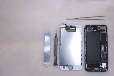 Akıllı telefonun bileşenleri, cımbız, demir çubuk ve küçük bir tornavida da dahil olmak üzere paslanmaz aletlerin yakınında parçalara ayrıldı..