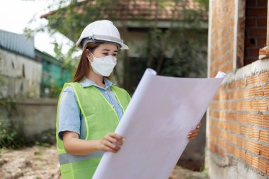 Mühendis konsepti. Beyaz maske takan ve miğfer takan kadın mühendis..
