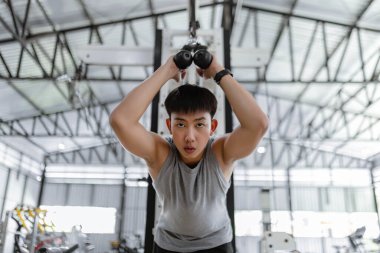 Spor konsepti. Spor kulübünde güç makinesi yapan, kendini eğen ve esnek halatı aşağıya doğru çekmeye çalışan ciddi yüzlü spor adamı..