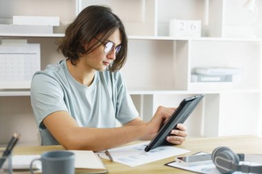 Uzaktan eğitim konsepti, takvim sınıfını kontrol eden genç çocuk ve evdeki tablette internet eğitimi..